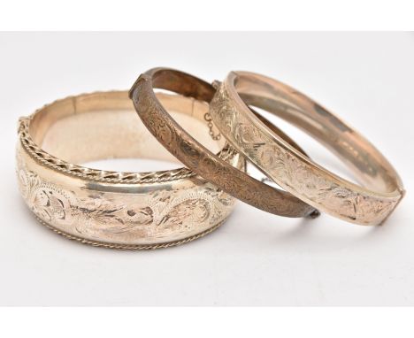 THREE SILVER HINGED BANGLES, to include a wide bangle with foliate pattern, push button clasp and additional safety chain, ha