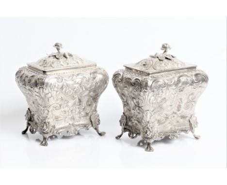 A pair of George IV silver decorative tea caddies with rose finials, ornate floral decoration to shaped body with heads at th