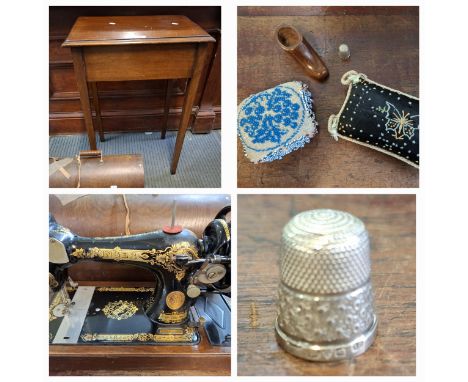 A 1920's mahogany sewing table and contents to include pin cushions, a small wooden clog and a silver thimble together with a
