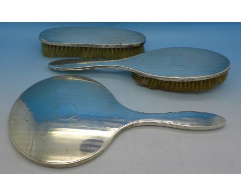 A silver backed mirror and two brushes