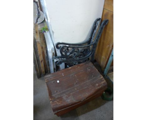A pair of cast iron bench ends and a tin steamer trunk 