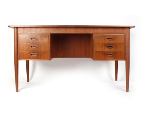 A 1970's teak desk, the rectangular surface above an arrangement of six drawers and having a shelf verso on turned tapered le