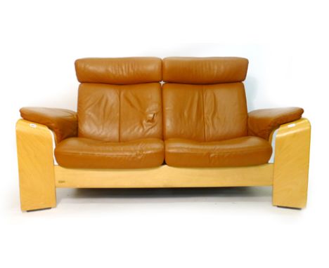 An Ekornes stress-less tan leather two seater sofa on a beech bentwood frame CONDITION REPORT: Wear commensurate with age and