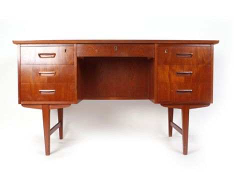 A 1970's teak desk, the rectangular surface above an arrangement of seven drawers and having a shelf verso on square tapered 