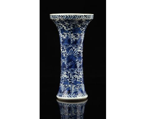 A small blue and white trumpet vase, decorated with typical panels of floral or natural history designs, 18.5 cm high, Kangxi