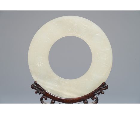 A Chinese pale celadon jade bi disc, Ming or earlier     Dia.: 11,5 cm (the ring)H.: 20,5 cm (stand incl.)  The stand of late