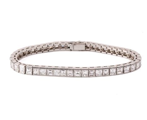A diamond line bracelet, incorporating forty-seven graduated square step-cut diamonds channel-set in articulated basket links