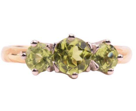 A three-stone peridot ring in 18ct gold, coronet-set with three graduated circular-cut peridot, of bright olive green colour,