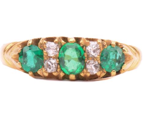 An emerald and diamond half hoop ring, set with three emeralds, the largest measuring 4mm x 3.2mm, with pairs of old cut daim