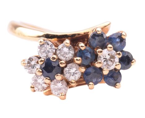 A sapphire and diamond double daisy cluster ring set with round brilliant cut diamonds and sapphires to a cross-over design r