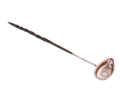 A George III white metal toddy ladle, the unassayed bowl with inset silver sixpence dated 1787, with part barley twist baleen