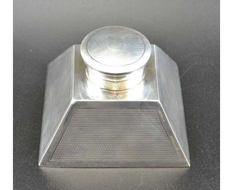 An early 20th century silver desk inkwell, pyramid form, the sloping sides engine turned, leather inset base, the hinged cove