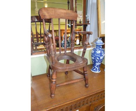 A provincial child's open arm stick back potty chair, elm seat, Windsor type, raised on turned supports with stretchers