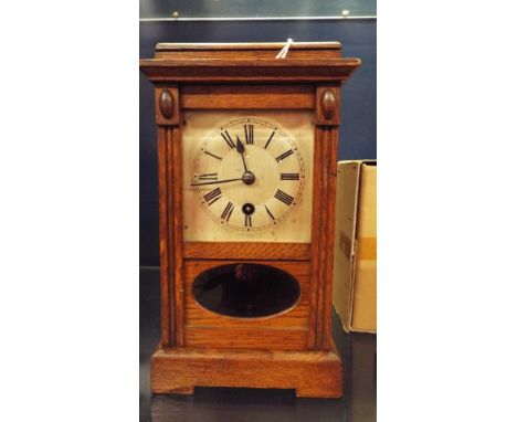 An oak cased mantle clock with oval glass pendulum view, silvered dial and Roman numerals