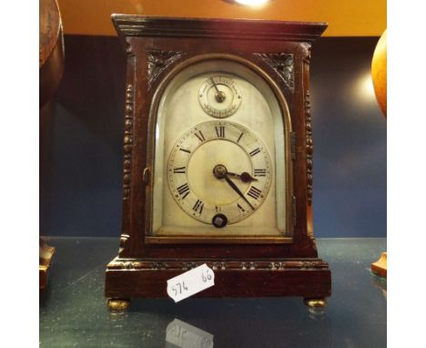 A mahogany cased mantle clock having silvered dial with Roman numerals and resting on brass bun feet, in working order with k