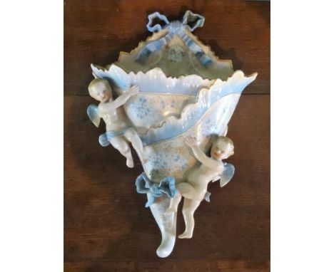 A 19th century ceramic wall pocket, surmounted by twin putti, with ribbon bow motif, blue crossed sword mark to reverse, impr