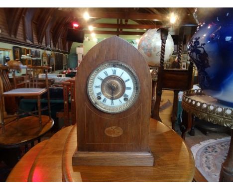 An Edwardian and inlaid arch top mantle clock, the enamel dial bearing Roman numerals (34cm).