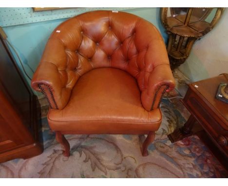 A tan leather button back tub chair on front cabriole supports (68cm wide).