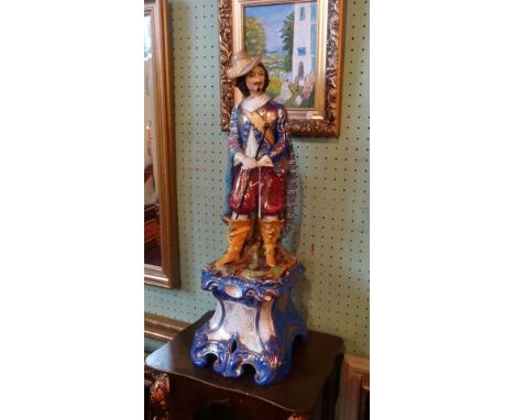 A Continental ceramic figuring of imposing proportions, a smartly dressed gentleman in polychrome enamel, on conforming rococ