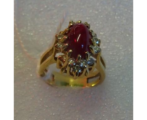 A cabochon ruby and diamond cluster ring, the oval ruby in claw mount, within a border of brilliant cut diamonds set at vario