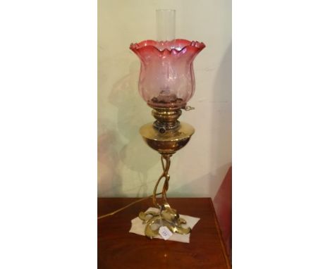 A late 19th century brass oil lamp, later converted to electricity, the Art Nouveau stylized base  beneath an acid etched cra