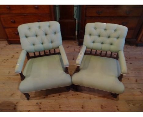 A pair of Victorian green upholstered button back armchairs on turned front supports (62cm wide).