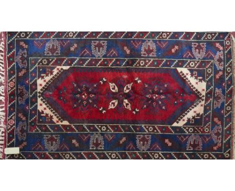 A Persian carpet with floral diamond medallion on a red and blue ground contained by geometric borders. 195 x 120cm 