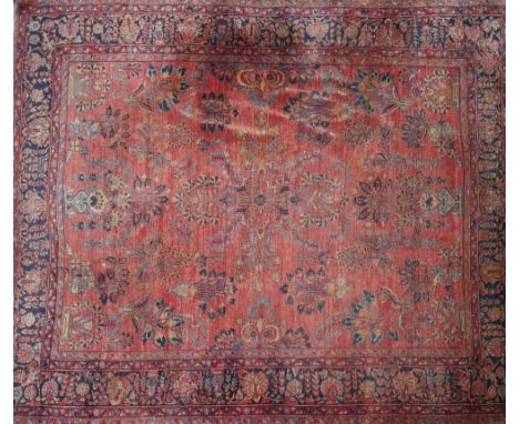 A large 20th century Sarouk carpet, with repeating floral motifs on a red and blue ground, contained by floral borders, 357 x