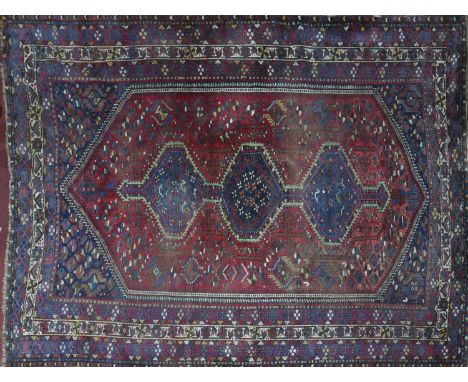 An antique Qashqai carpet with triple pole diamond medallion, within a lozenge field, on a red and blue ground, contained by 