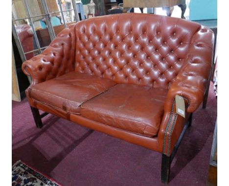 A 'Pegasus' Chesterfield style sofa with tan leather button back upholstery, raised on reeded mahogany legs joined by stretch