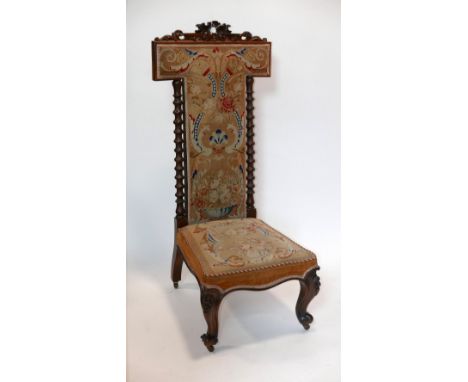 A Victorian rosewood prie dieu chair with tapestry upholstery, barley twist supports, raised on castors 