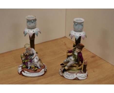 A pair of late 19th/early 20th century Sitzendorf porcelain figural candlesticks, one ornamented with young girl feeding a go