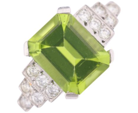 An Art Deco style platinum peridot and diamond ring, claw set with 2.5ct octagonal step-cut peridot flanked by modern round b
