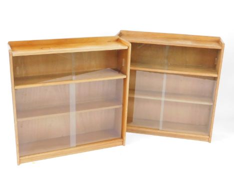 A pair of 1960's/70's light oak bookcases, each with two sliding glass doors, enclosing two shelves, each 93cm high, 92cm wid