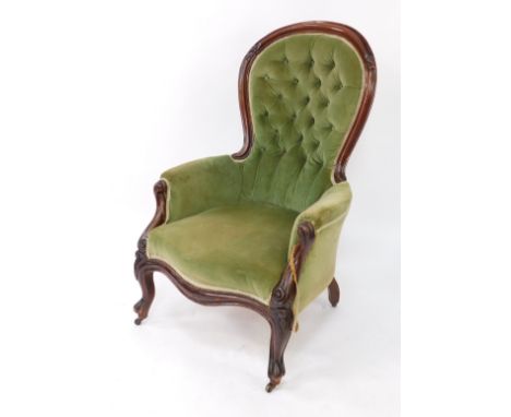 A Victorian mahogany spoon back armchair, upholstered in button back green velour, raised on cabriole legs, on castors. 