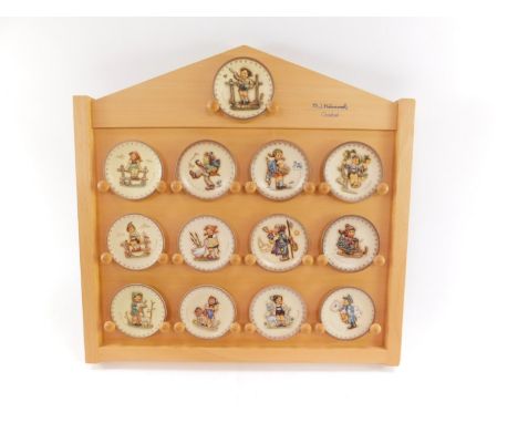 A group of Goebel Hummel collector's plates, on wooden display stand, to include Nos 990., 987., 988., 983., 972., 975., 992.