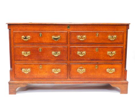 A George III oak and mahogany cross banded Lancashire chest, with a hinged top above four dummy drawers and two frieze drawer
