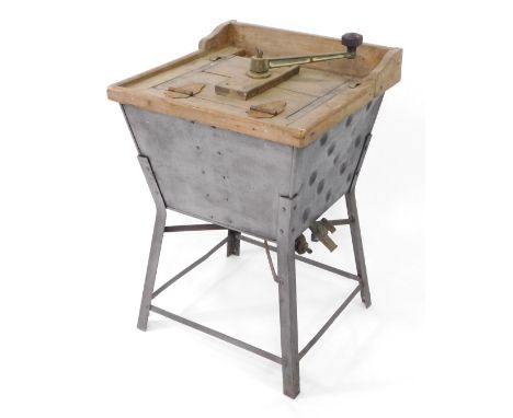 An early 20thC manual washing machine, with wooden frame and turned metal handle on galvanised bucket, on four claw base with