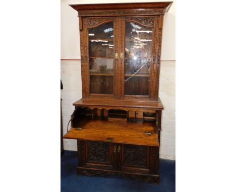 A Victorian oak secretaire bookcase, the out swept pediment over a pair of glass fronted doors, with a leaf and foliate carvi