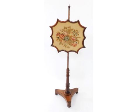 An early Victorian rosewood firescreen, the shaped screen with wool work floral tapestry, raised on a turned column, over a t