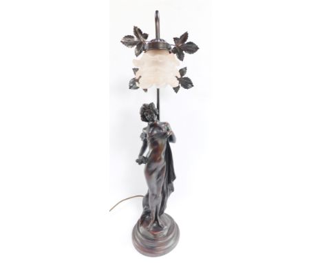 An early 20thC bronzed finish table lamp, with arched top, with leaf design and figure of a lady, on a stepped base with pink