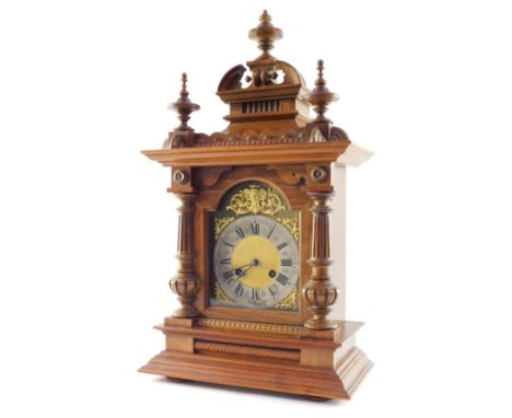 A Teutonia Glock Manufactory late 19thC walnut cased mantel clock, the break arch brass dial with gilt mask and scroll spandr