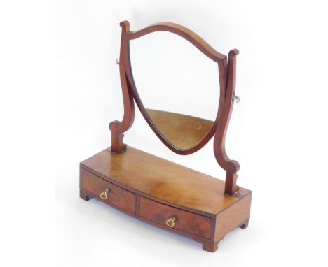 An Edwardian mahogany toilet mirror, the shield shaped mirror on two supports, over a bow fronted base with two frieze drawer