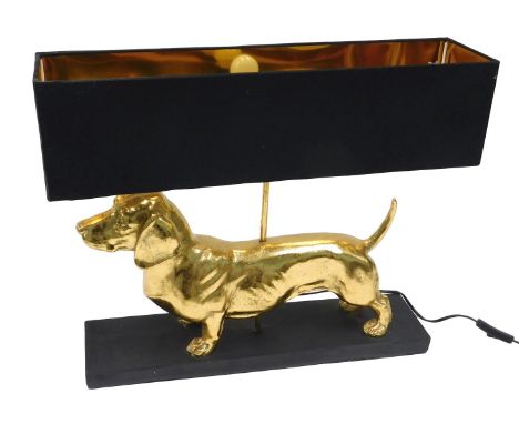 A modern table lamp, modelled in the form of a gold coloured Dachshund, with black shade and ebonised base, 55cm wide.