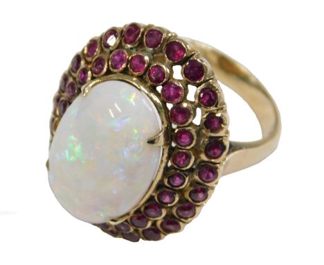 A gold opal and ruby ring, in a basket setting, the opal in a double row surround of rubies, one stone lacking, shank stamped