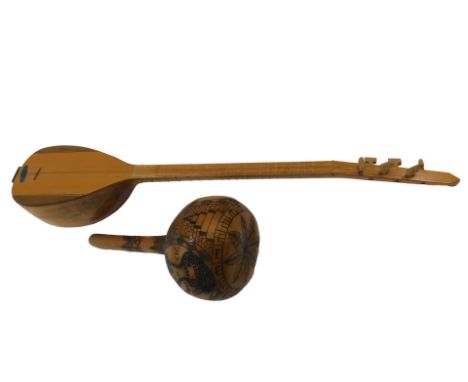 A Turkish Sas guitar with three pairs of strings, 79cm long, and a carved Cypriot gourd, decorated with a figure holding a co