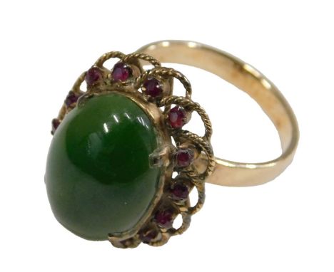 A gold jade and ruby ring, the oval cabochon jade in a surround of small rubies, within a basket setting, shank indistinctly 
