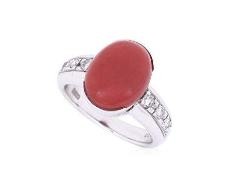 A RED CORAL AND DIAMOND RING
Featuring an oval cabochon red coral, mounted in a platinum setting marked 'PT900' to the shank,