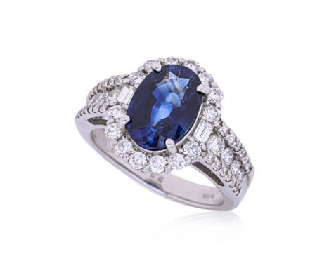 A BLUE SAPPHIRE AND DIAMOND CLUSTER RING Featuring an oval sapphire weighing approximately 2.828 Cts (marked), mounted on a p