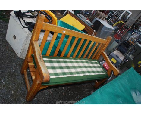 A heavy oak garden bench with cushion and protective waterproof cover.